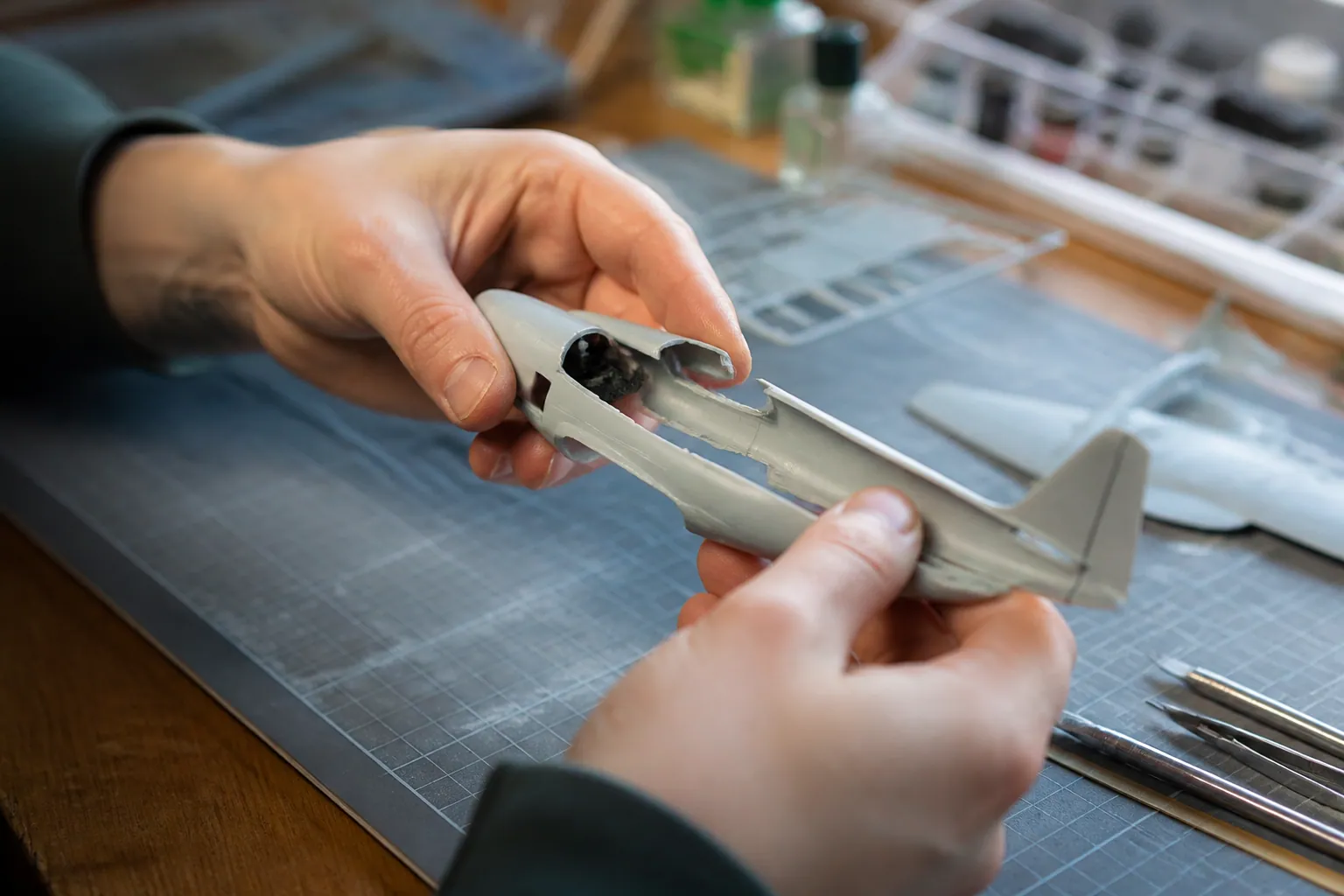 Mains assemblant délicatement le fuselage d’une maquette d’avion